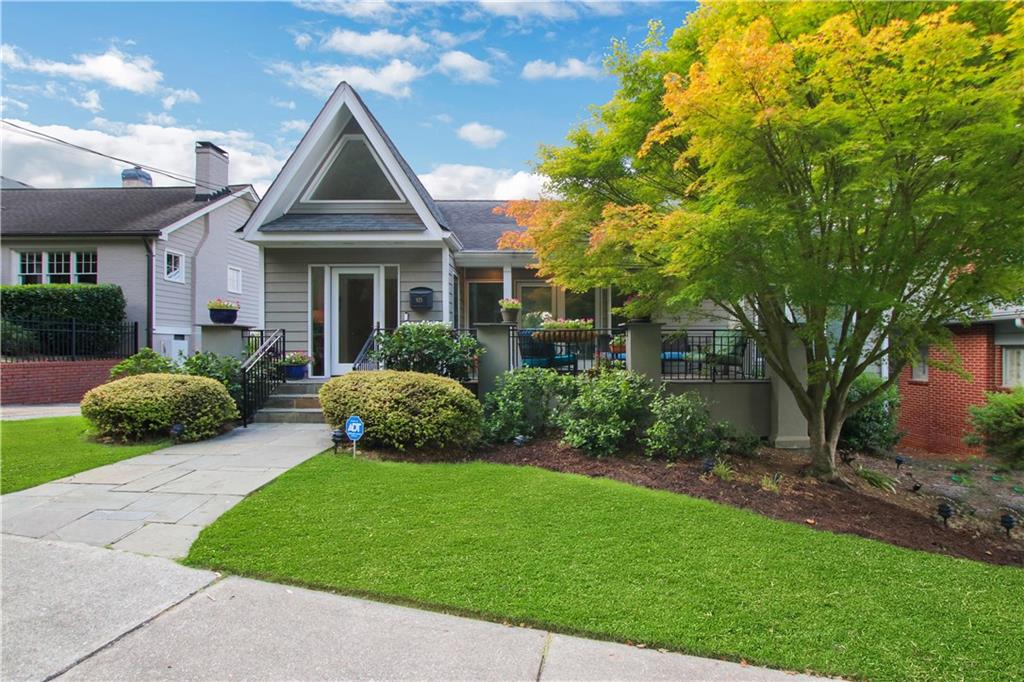 Gray-sided home with a prominent gable, landscaped front yard, and large tree with yellowing leaves.