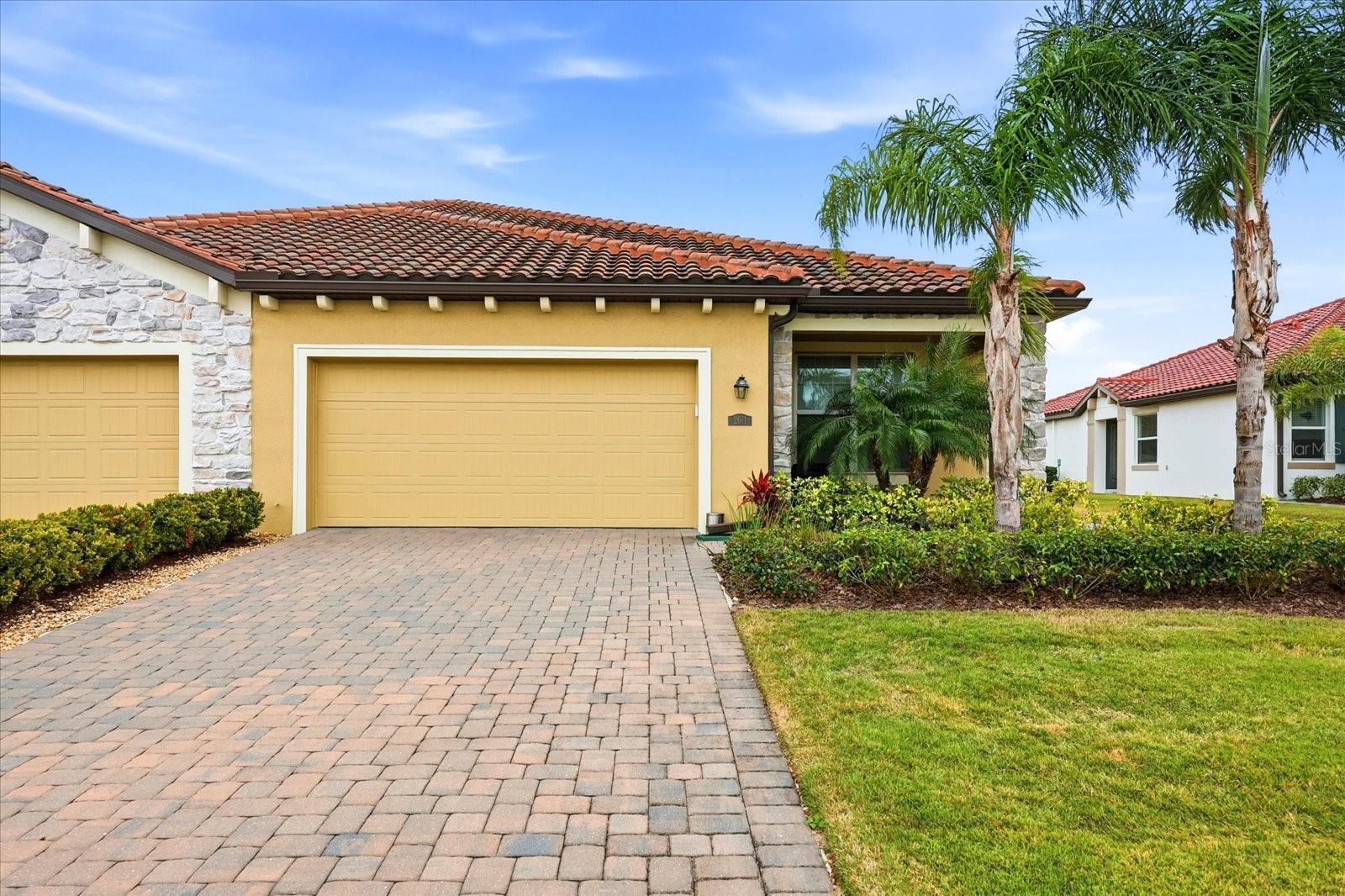 Home at 2611 Avolet Ct with a red tile roof, paver driveway, and palm trees.