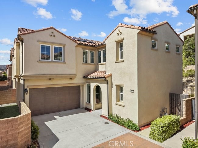 Two-story stucco house with a tiled roof, double garage, and wide driveway.