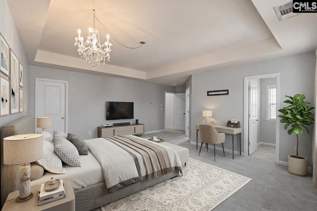 Furnished bedroom with a crystal chandelier, tray ceiling, and desk beside the doorway.