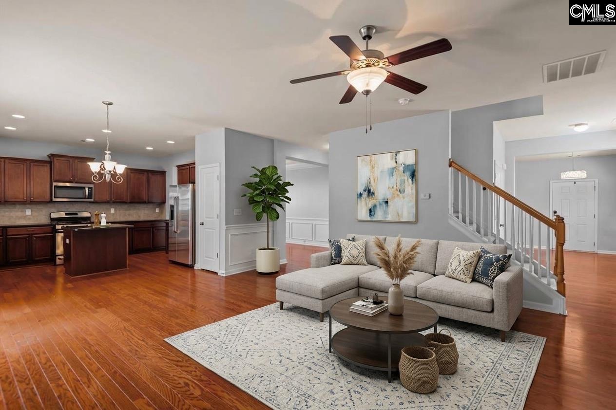 Open-plan living room and kitchen with a gray sectional, hardwood floors, and dark wood cabinetry.
