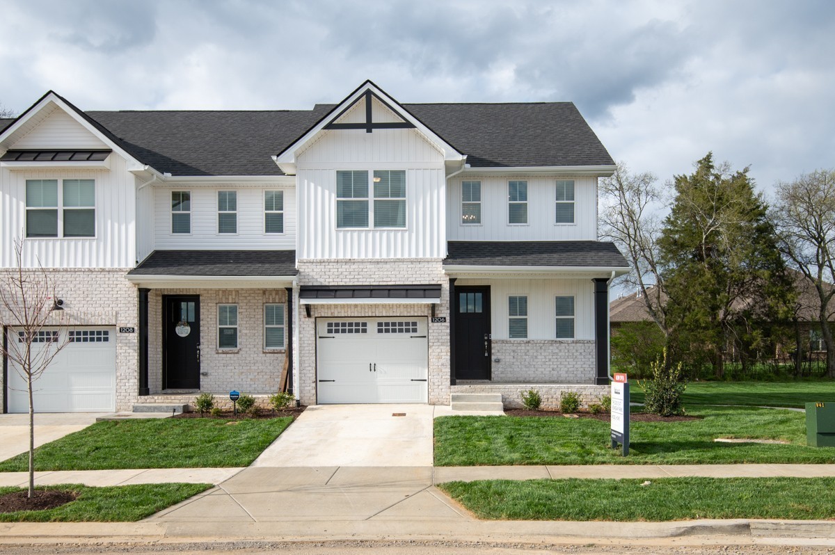 Two attached white homes with brick lower facades, dark roofs, and separate driveways.