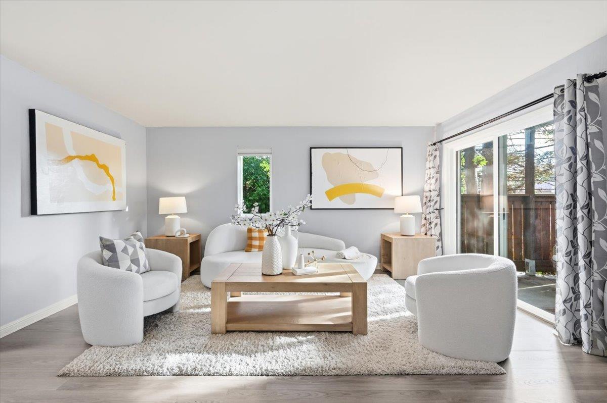 Staged living room with white seating, abstract art, and sliding glass doors to a patio.