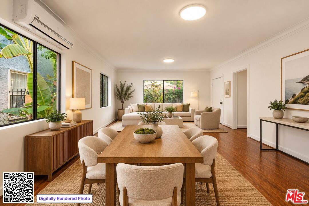 Dining room with a long wooden table, upholstered chairs, and an adjoining cream sofa seating area.