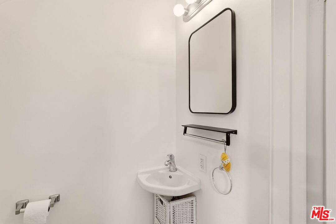 Bathroom with a wall-mounted sink, black-framed mirror, and towel rack.