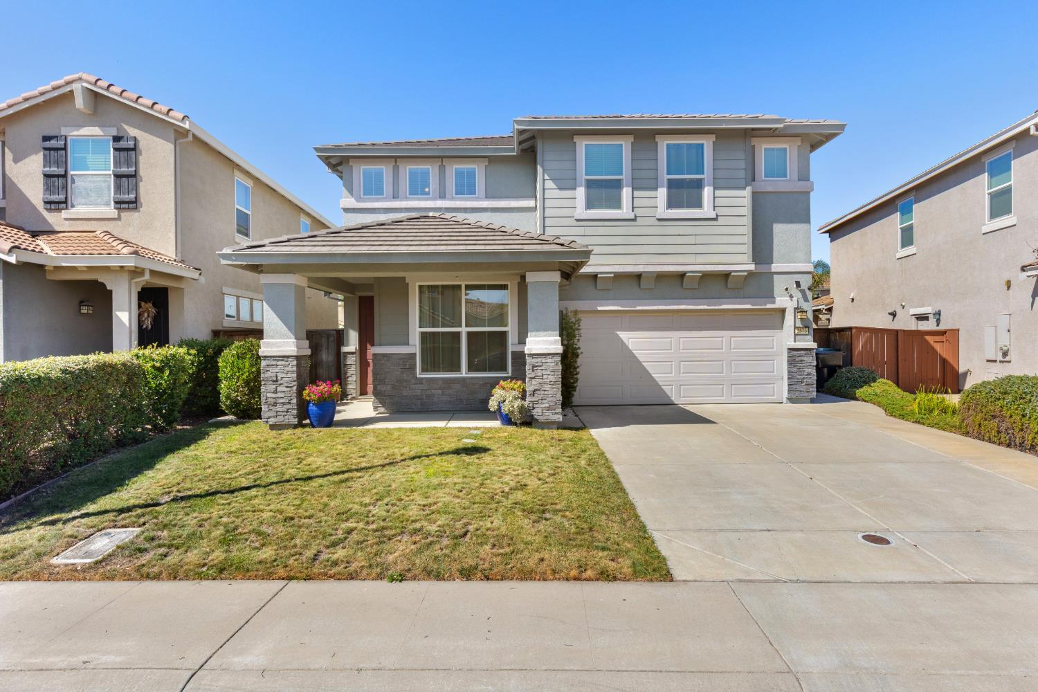 Two-story gray house with an attached garage, small lawn, and neighboring homes.