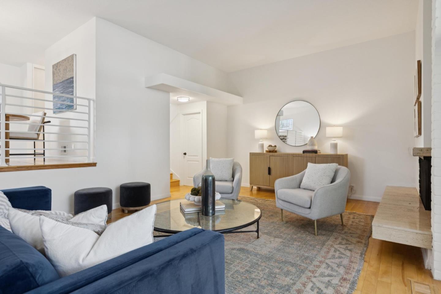 Staged living room with a blue sofa, gray armchairs, and a raised dining area.