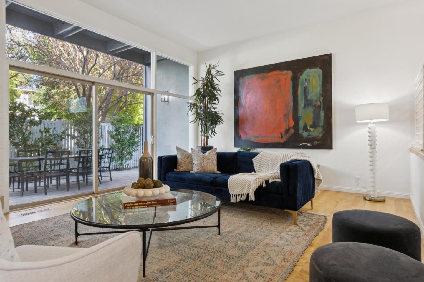 Living room with a navy sofa, large abstract painting, and sliding doors to a furnished patio.