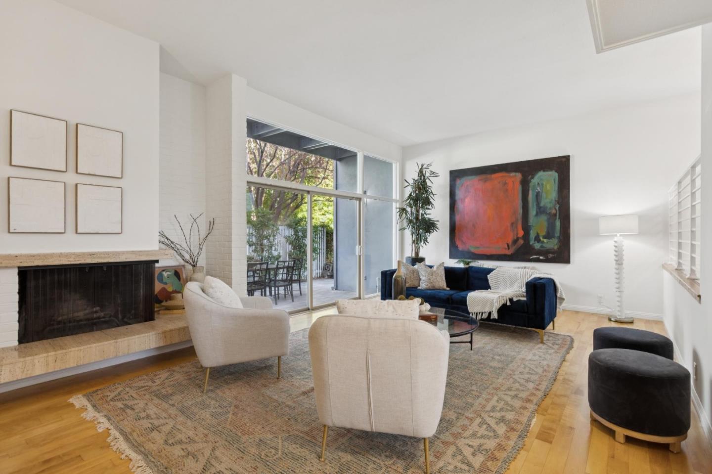 Living room with a stone fireplace, navy sofa, cream chairs, and glass doors to a patio.