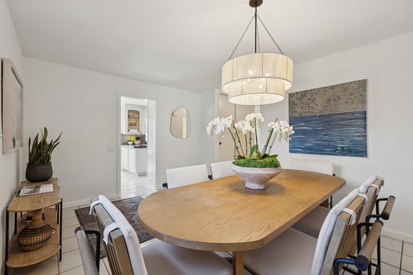 Dining room with an oval wood table, upholstered chairs, and a large pendant light.