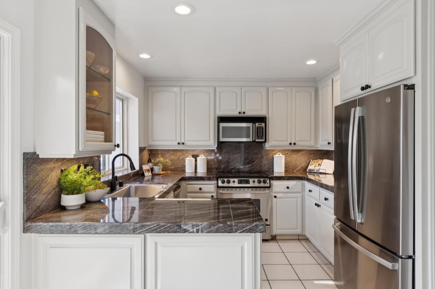 Kitchen with white cabinets, dark stone counters, and stainless steel appliances.