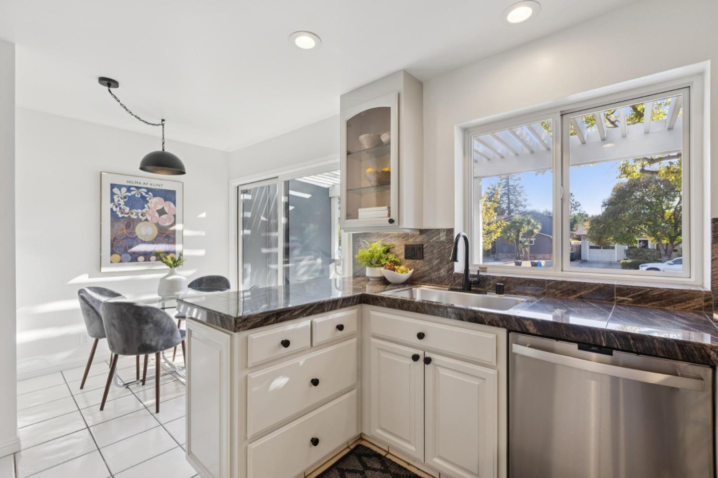 Bright kitchen with dark stone counters, white cabinetry, and a dining nook by the window.