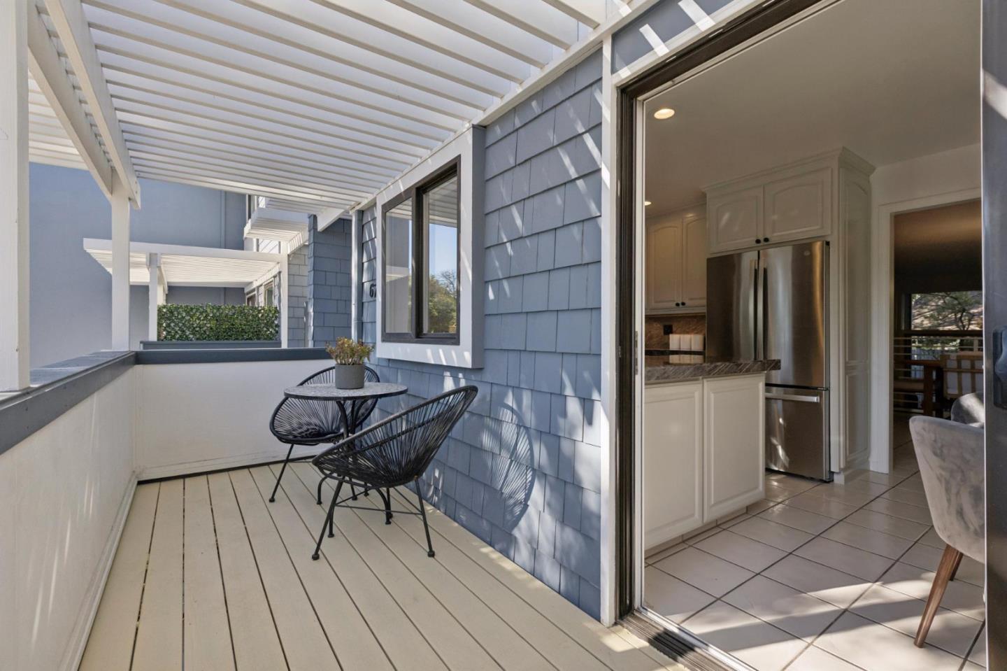 Covered balcony with black bistro set beside an open sliding door to the kitchen.