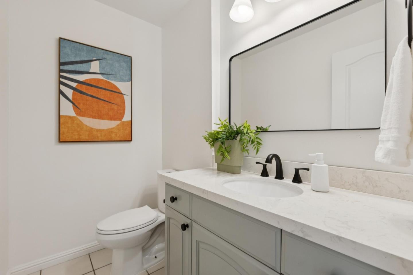 Bathroom with gray vanity, marble-look counter, black faucet, large mirror and abstract wall art.