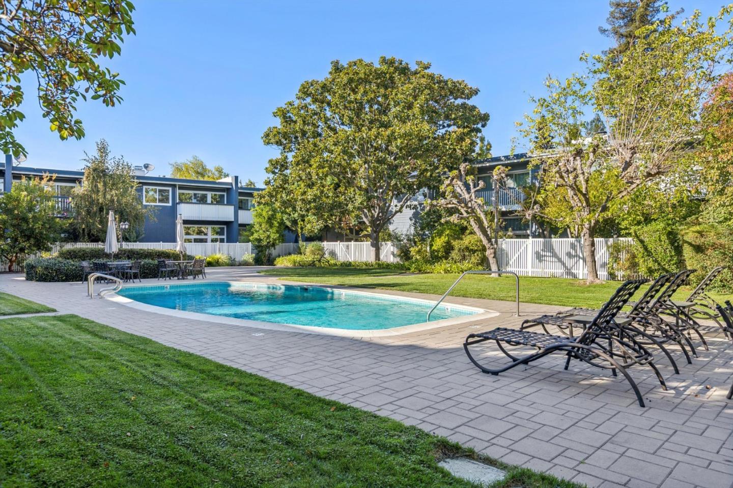 Outdoor swimming pool with lounge chairs beside a landscaped residential building.