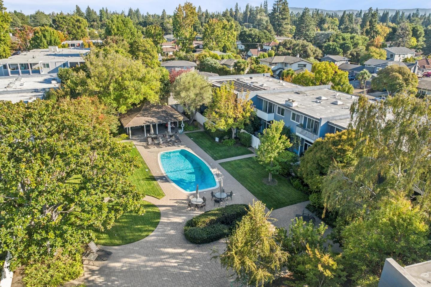 Aerial view of a residential complex with a turquoise pool, landscaped courtyard, and outdoor seating.