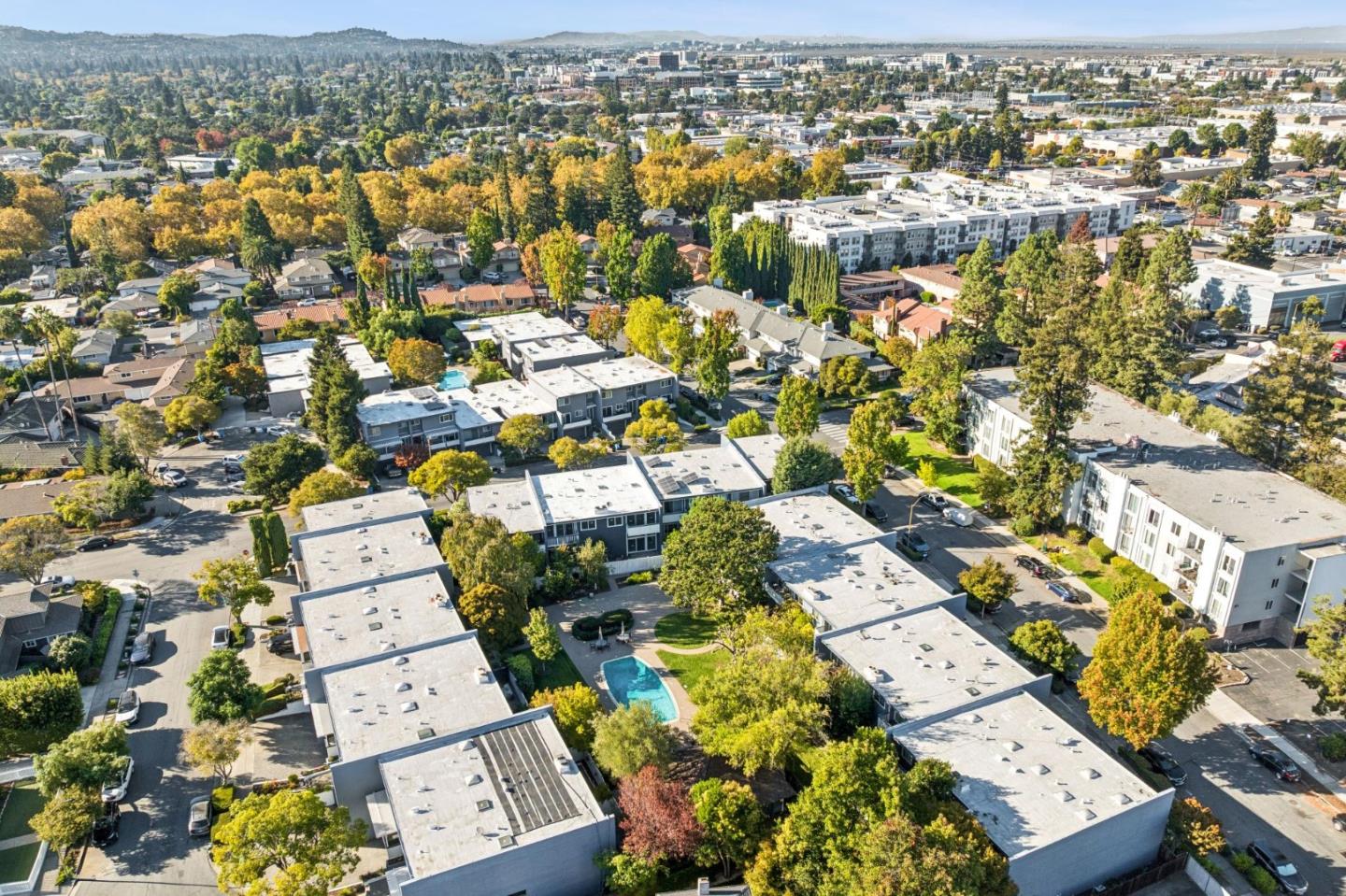 Aerial view of a tree-lined Redwood City neighborhood with residential buildings and a swimming pool.