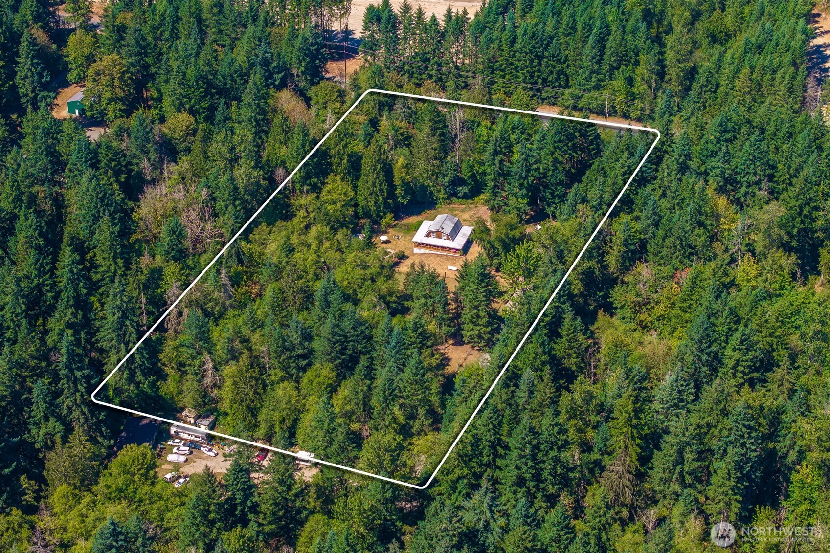 Aerial view of a wooded property outlined in white, with a house in a central clearing.