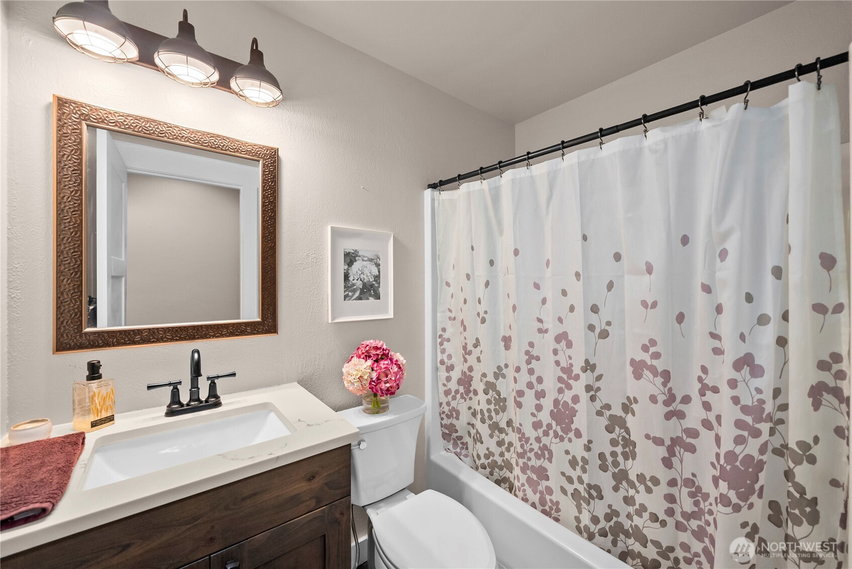 Bathroom with a dark wood vanity, framed mirror, and floral shower curtain.