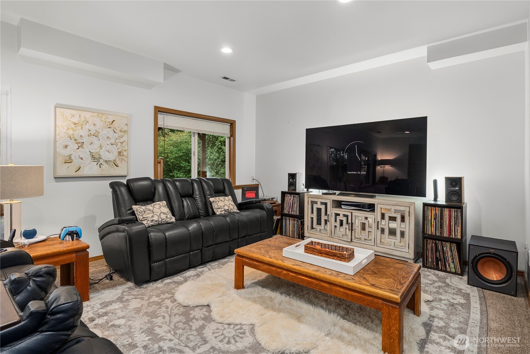 Media room with black leather recliners, a large television, and surround-sound speakers.