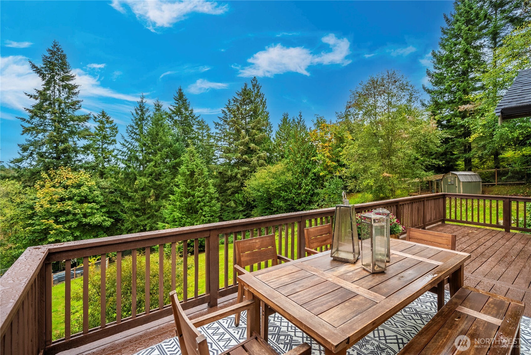 Wooden deck dining area overlooking a lush wooded yard.