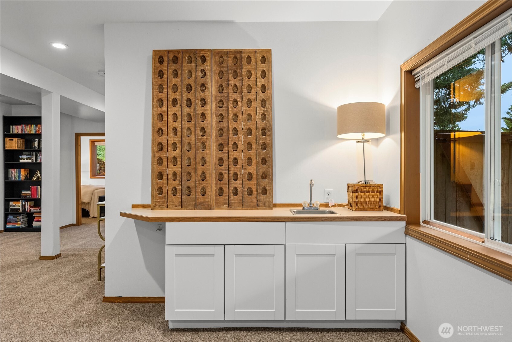 Wet bar with carved wooden panels, a small sink, and a large window.