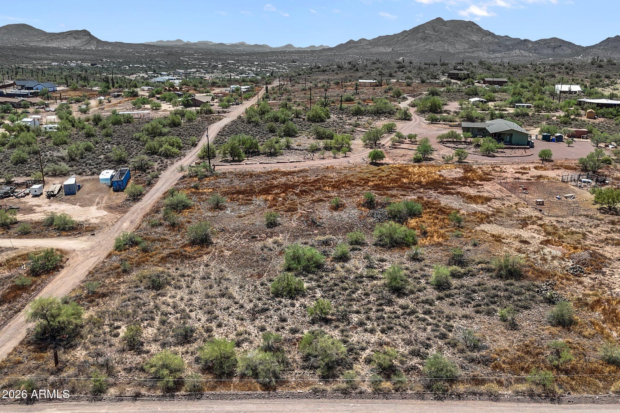 Aerial view of a vacant desert lot with sparse shrubs and mountains beyond.