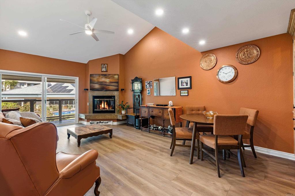 Living and dining room with a corner fireplace and sliding doors overlooking a pool.