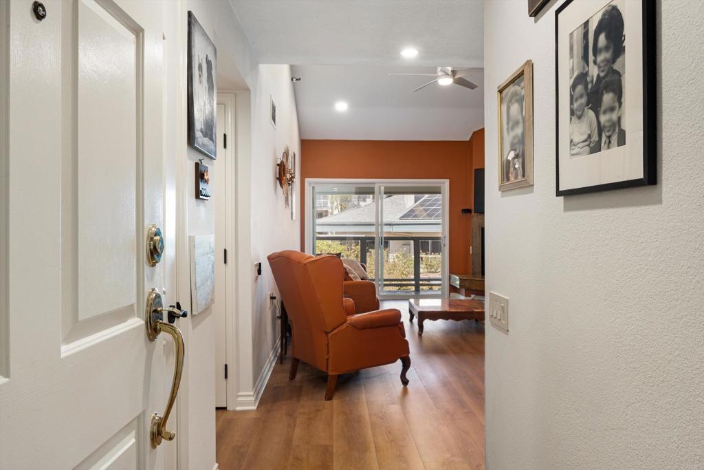 Living room with orange leather armchairs, wood floors, and sliding glass doors to a balcony.