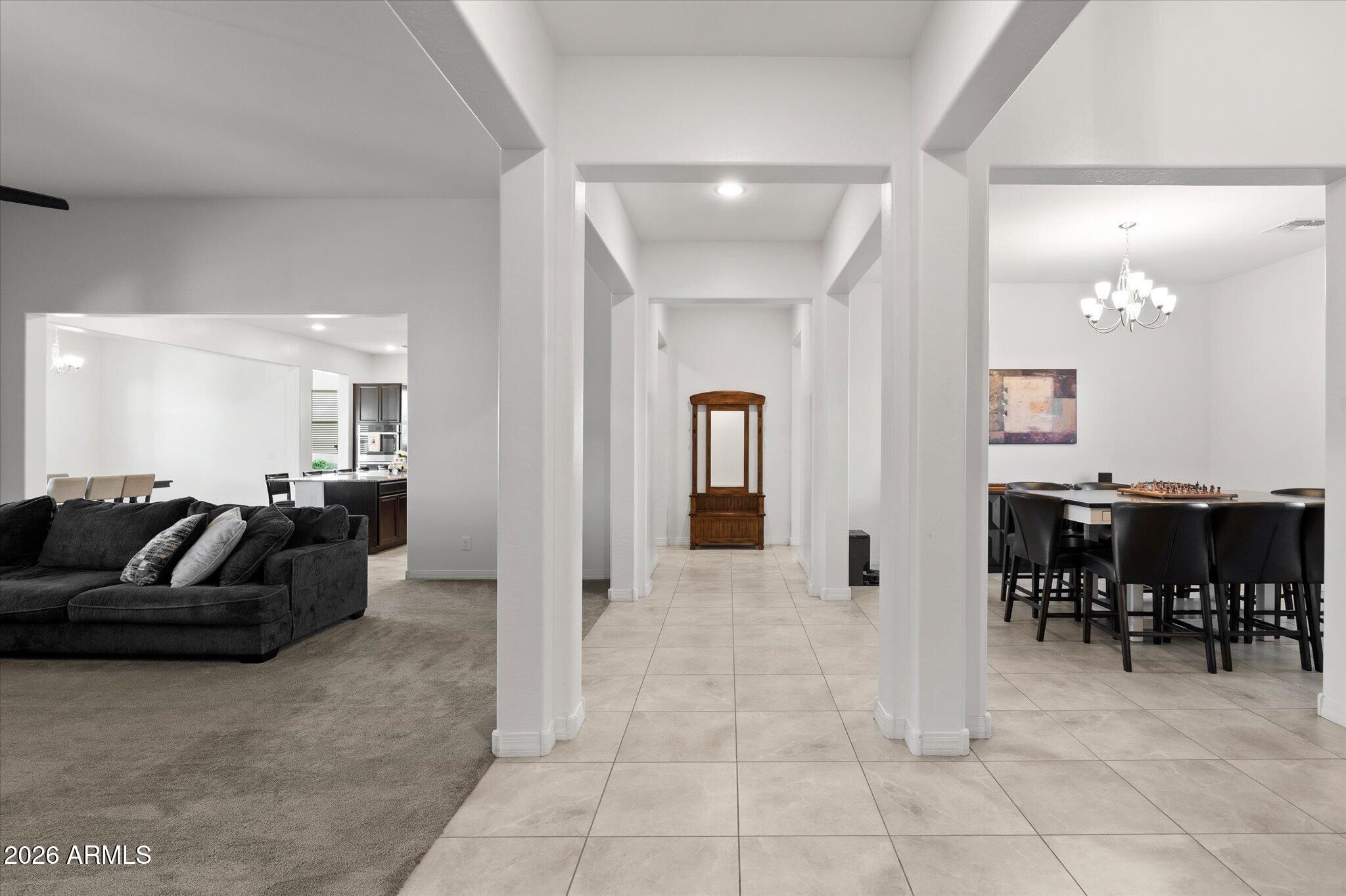 Open-plan interior with a tiled hallway between a carpeted living room and a dining area.
