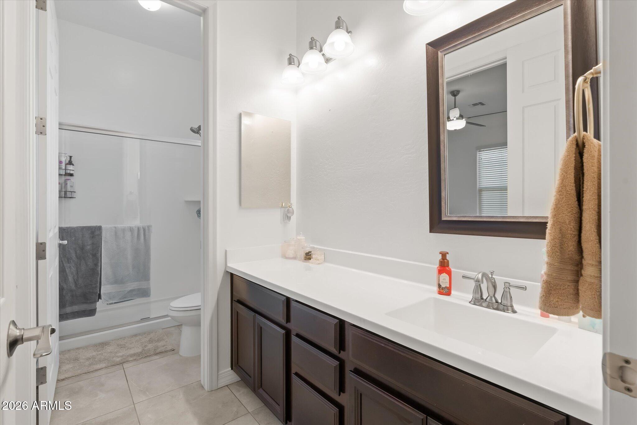 Bathroom with a long white vanity, dark cabinets, large mirror, and glass shower enclosure.