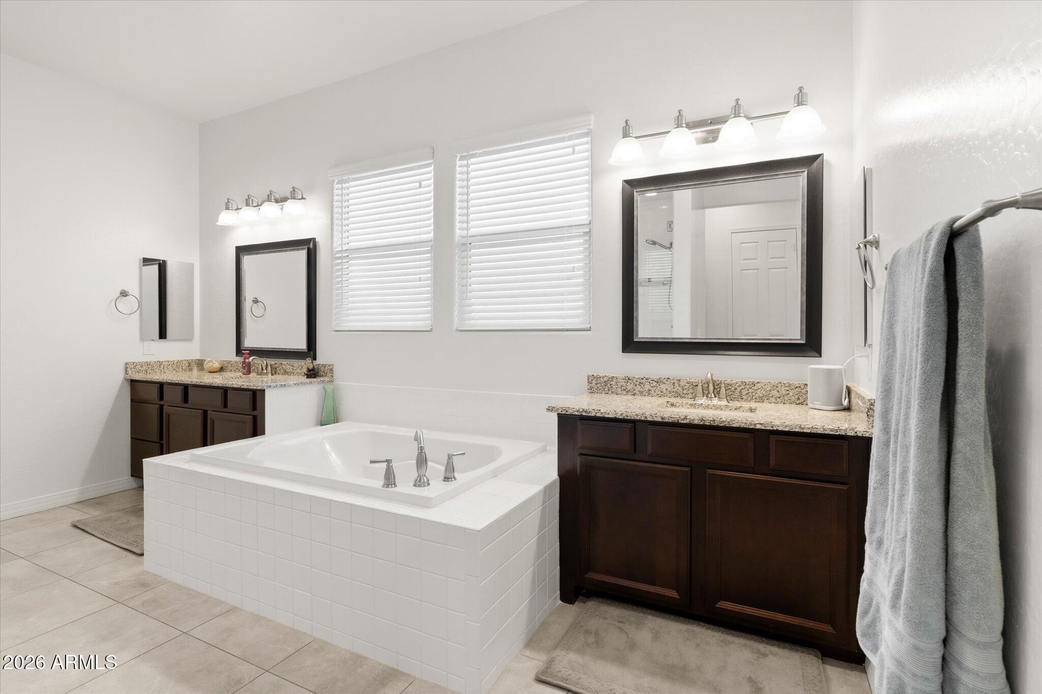 Bathroom with a built-in soaking tub and dark wood double vanity with granite counters.
