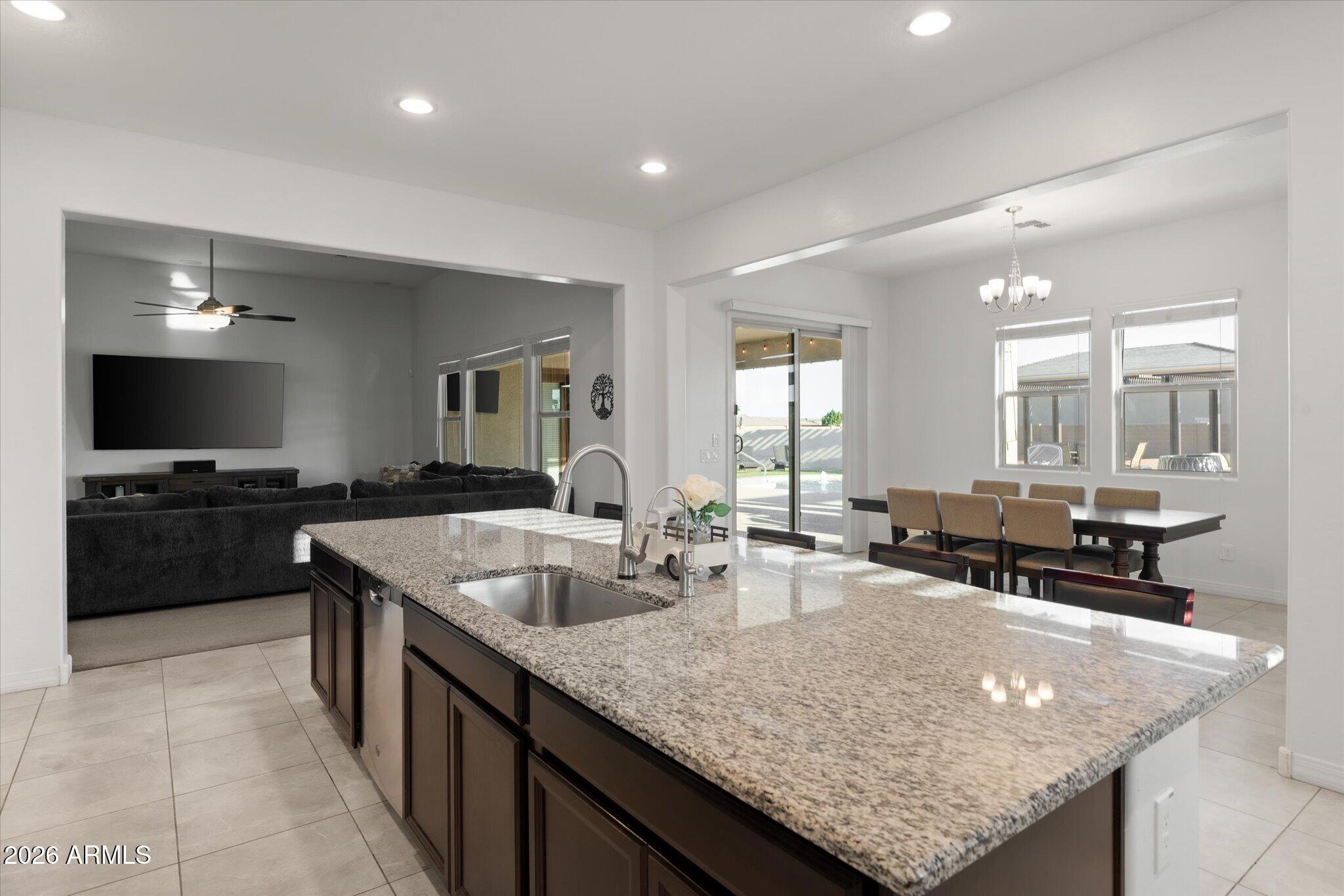 Open-plan kitchen with a large granite island and sink beside the dining area and living room.