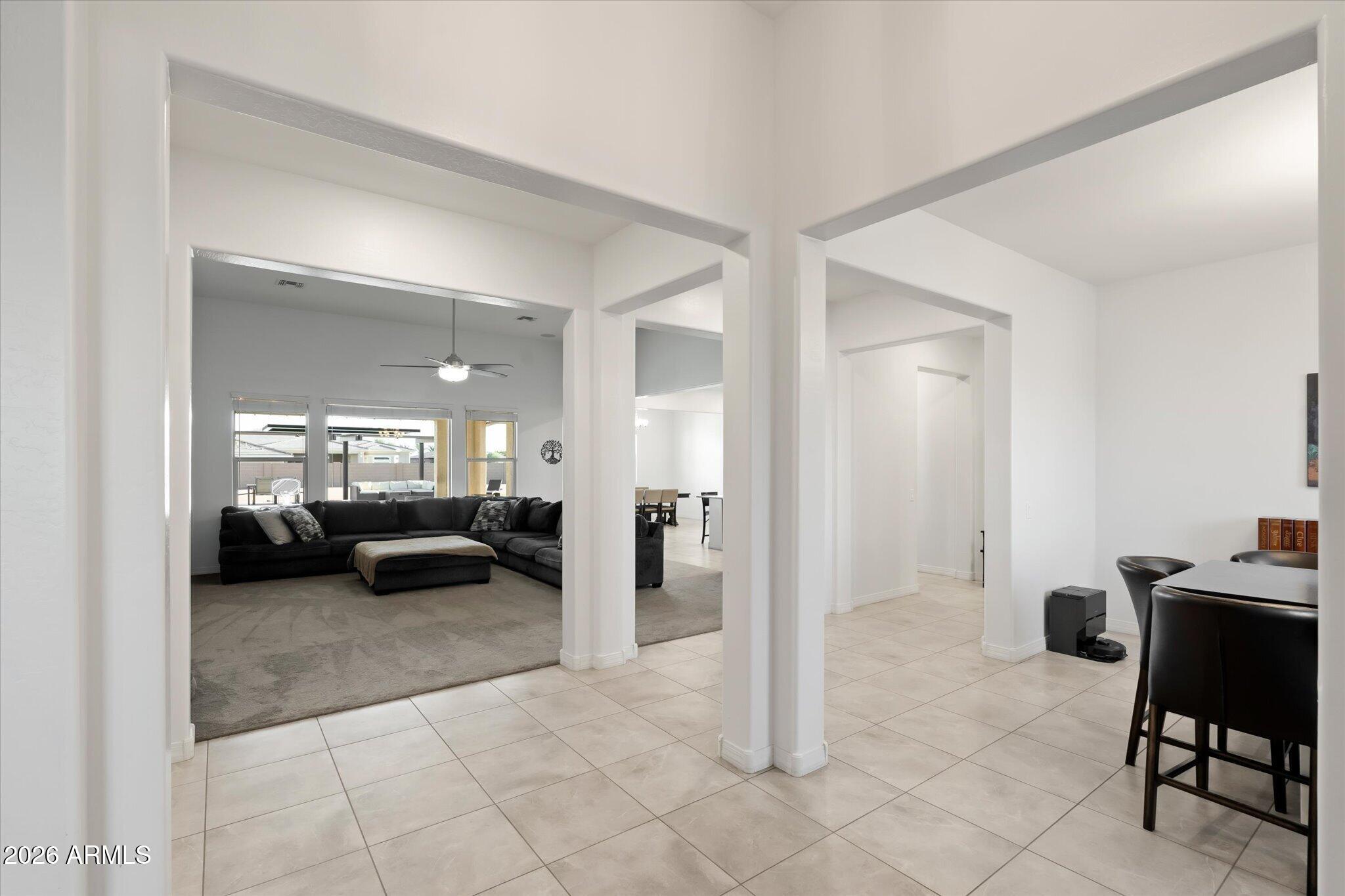 Open dining area leads to a carpeted living room with a charcoal sectional and large windows.