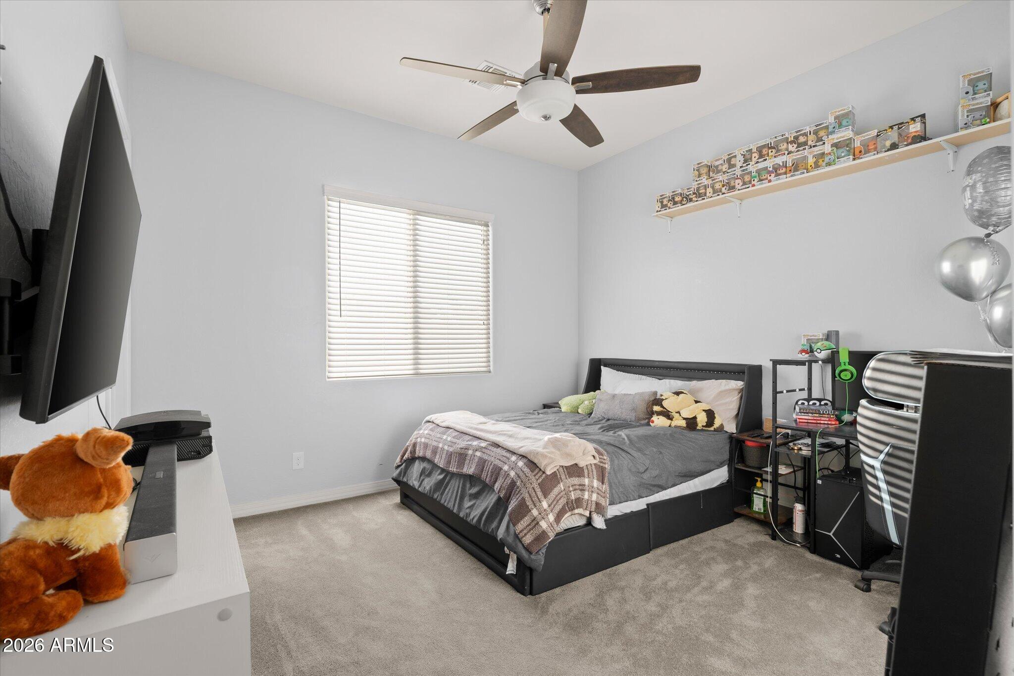 Bedroom with a dark platform bed, collectible figures on wall shelves, and gaming equipment.