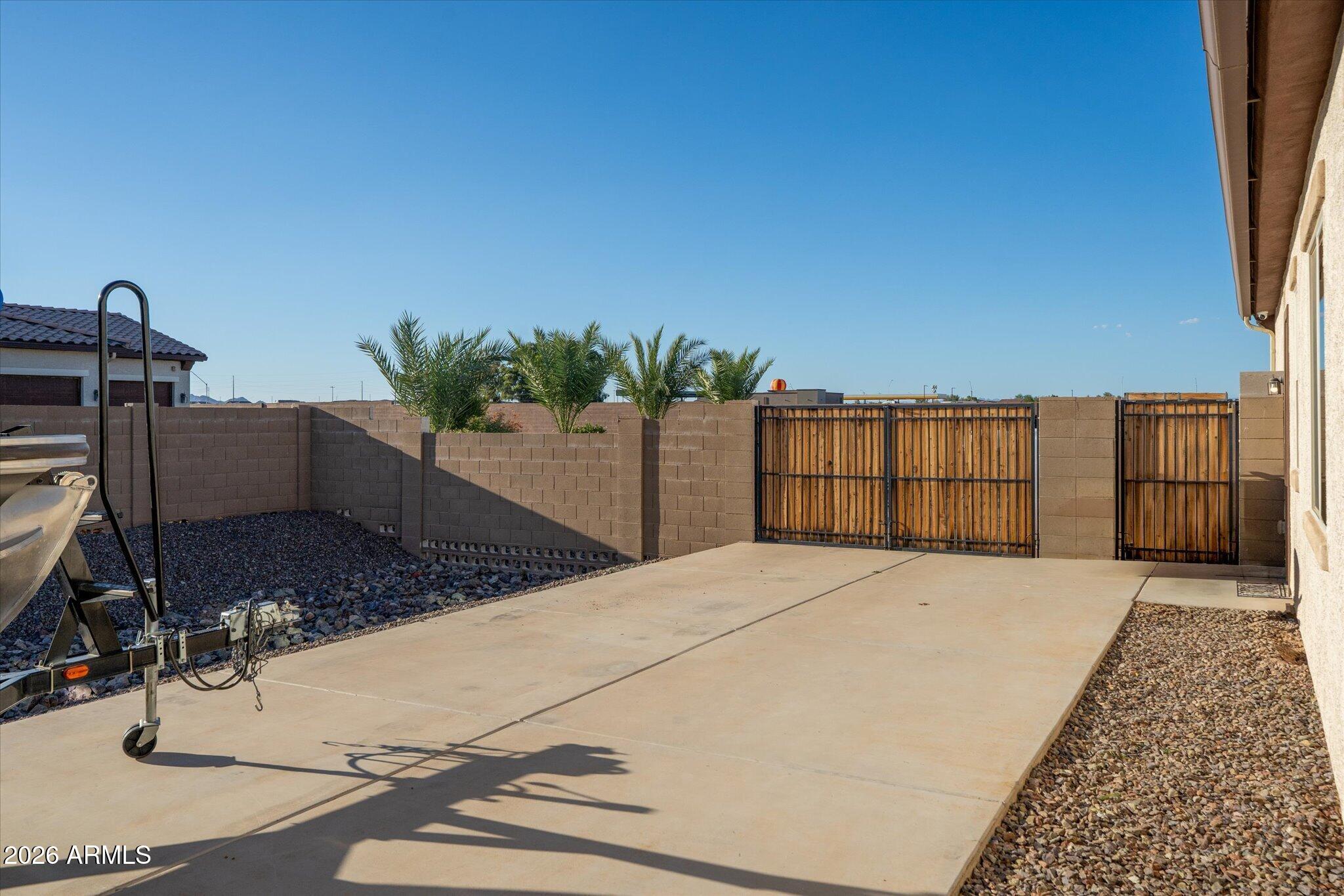Enclosed side yard with a concrete patio, gravel borders, block walls, and wooden gates.