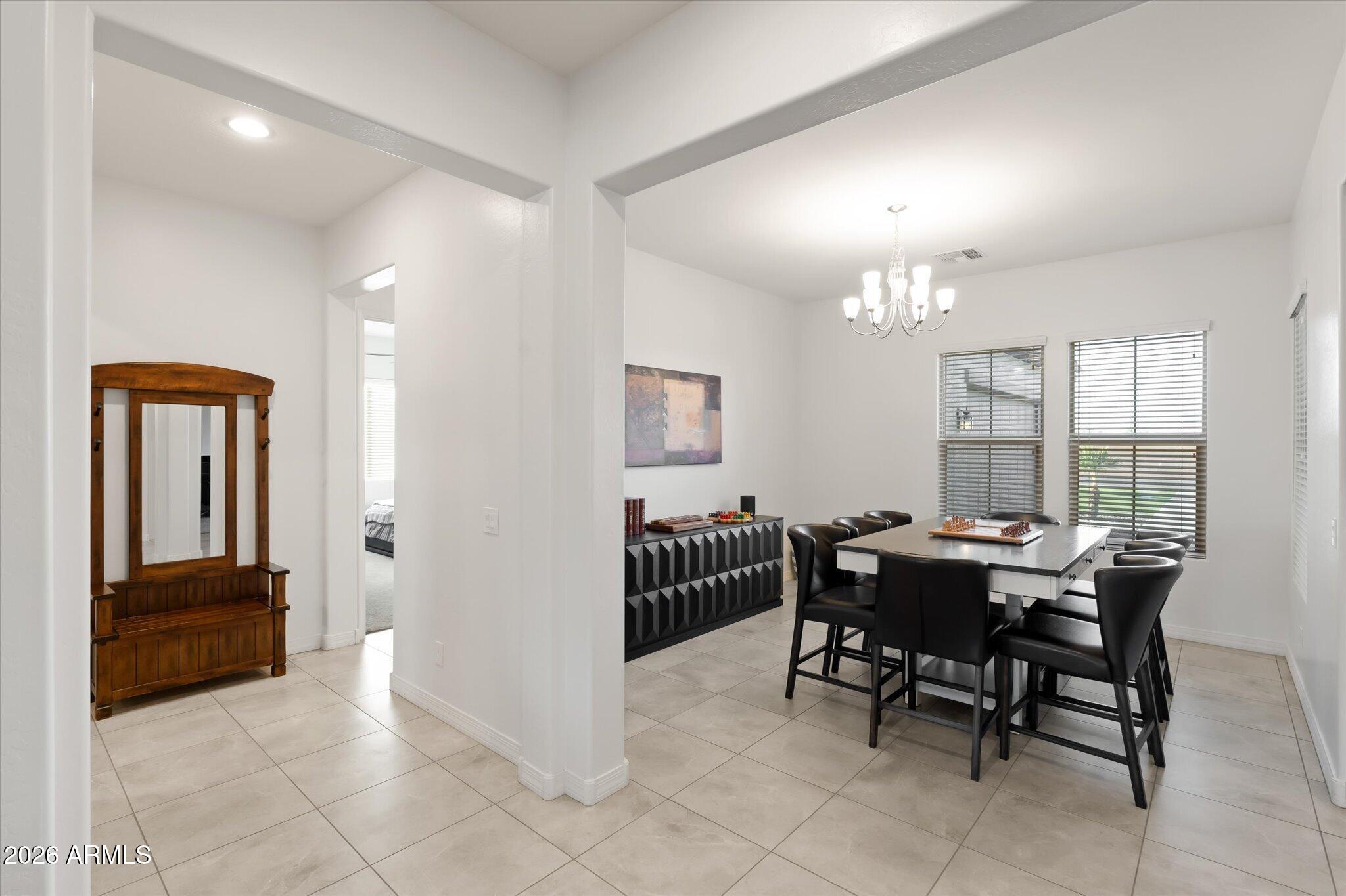 Dining room with a black table and chairs, chandelier, and geometric sideboard.