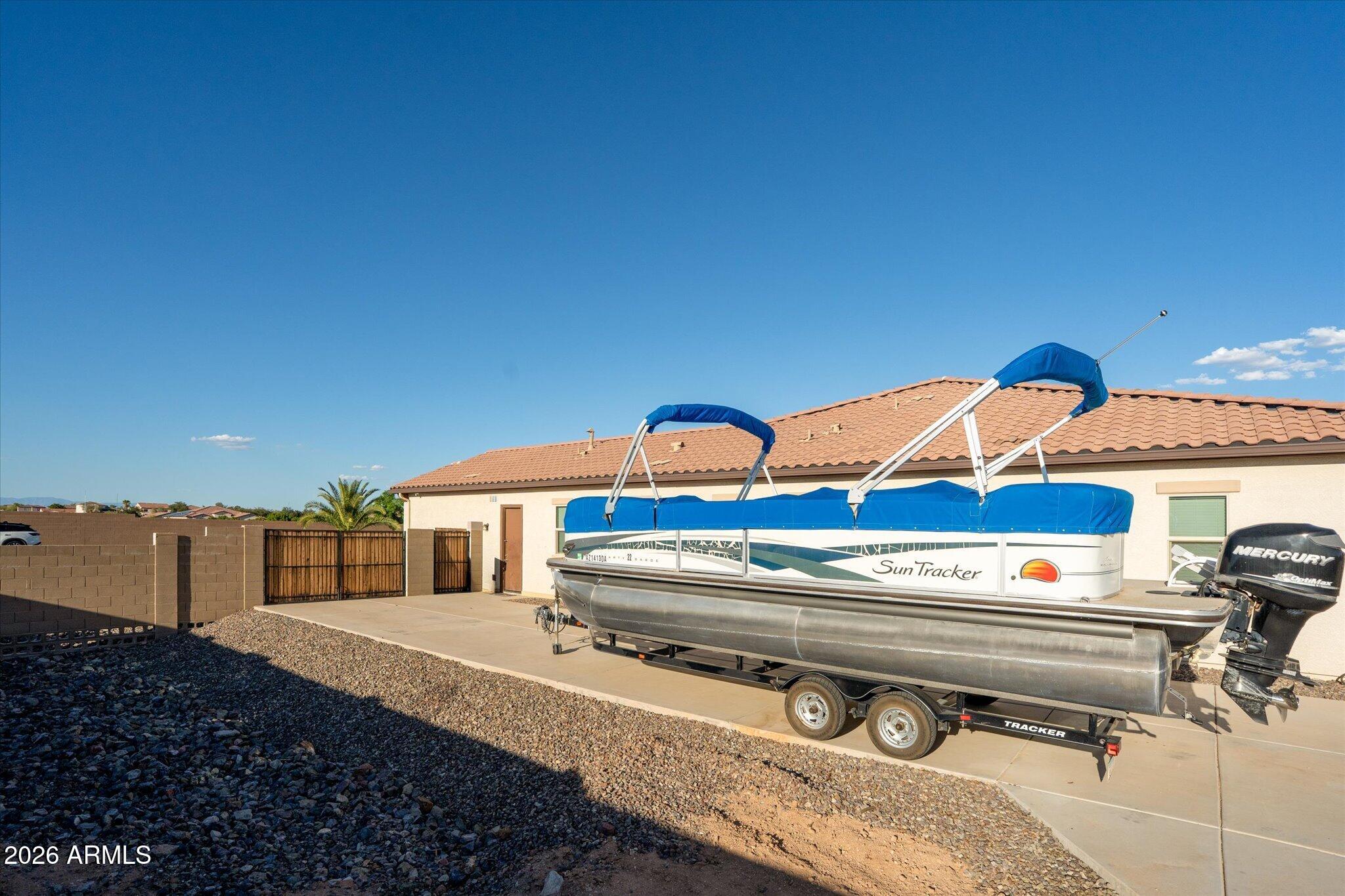 Single-story stucco home with a pontoon boat parked on the concrete driveway.