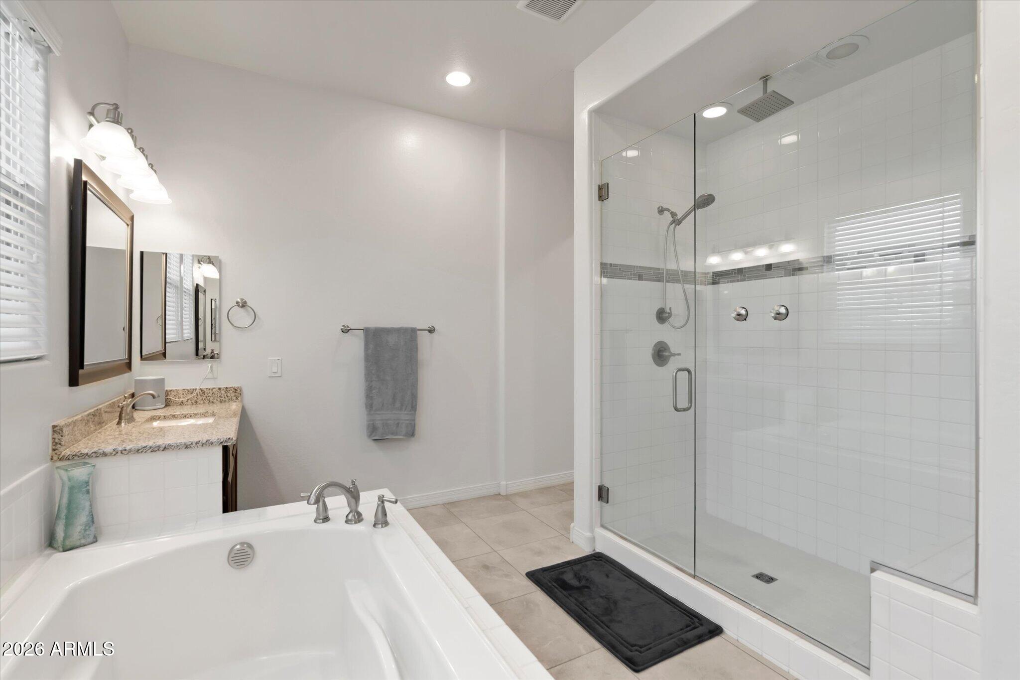 Bathroom with a soaking tub, granite vanity, and spacious glass-enclosed shower.