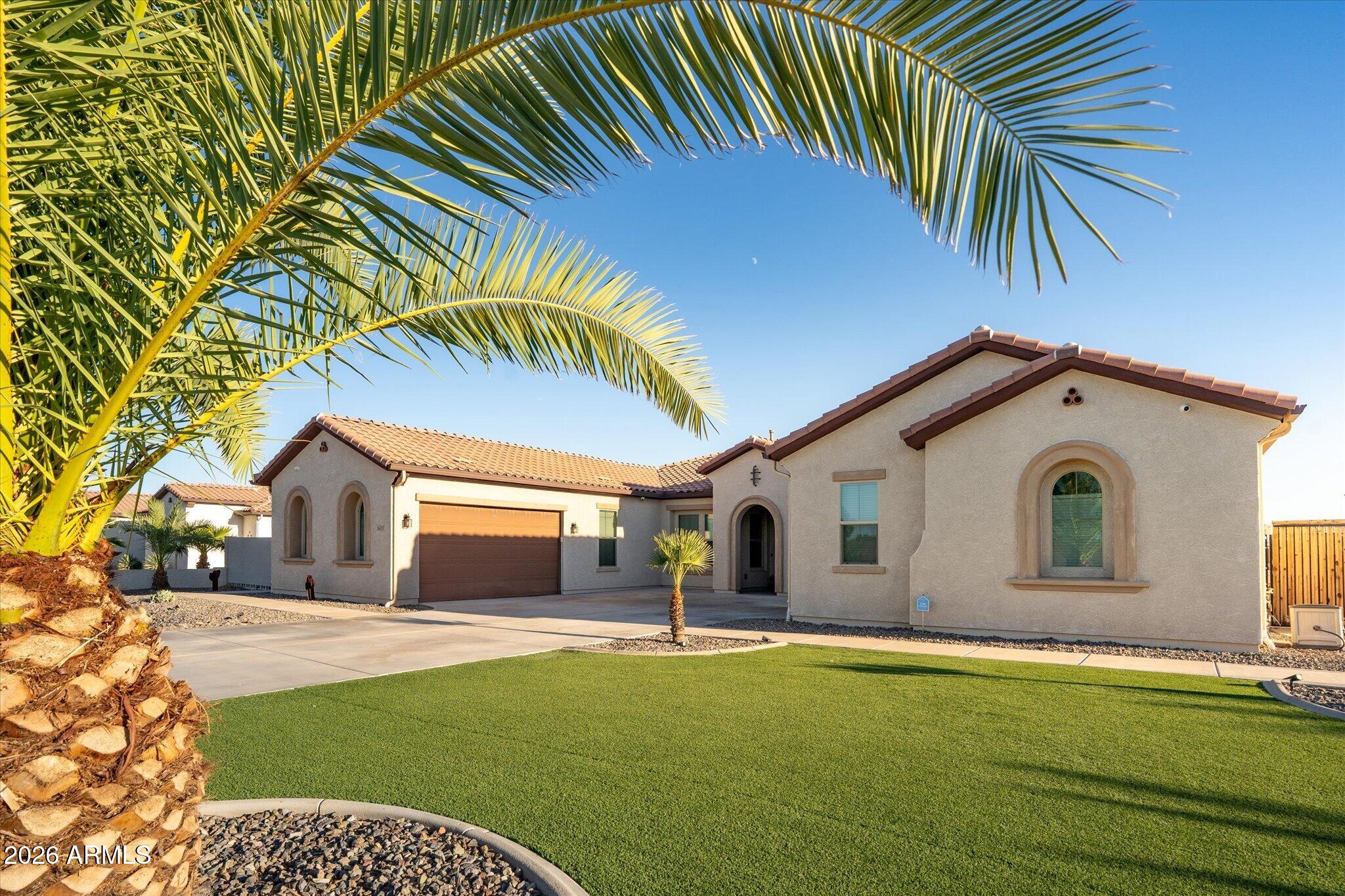 Single-story stucco home with arched windows, a tiled roof, and palm trees framing the front yard.