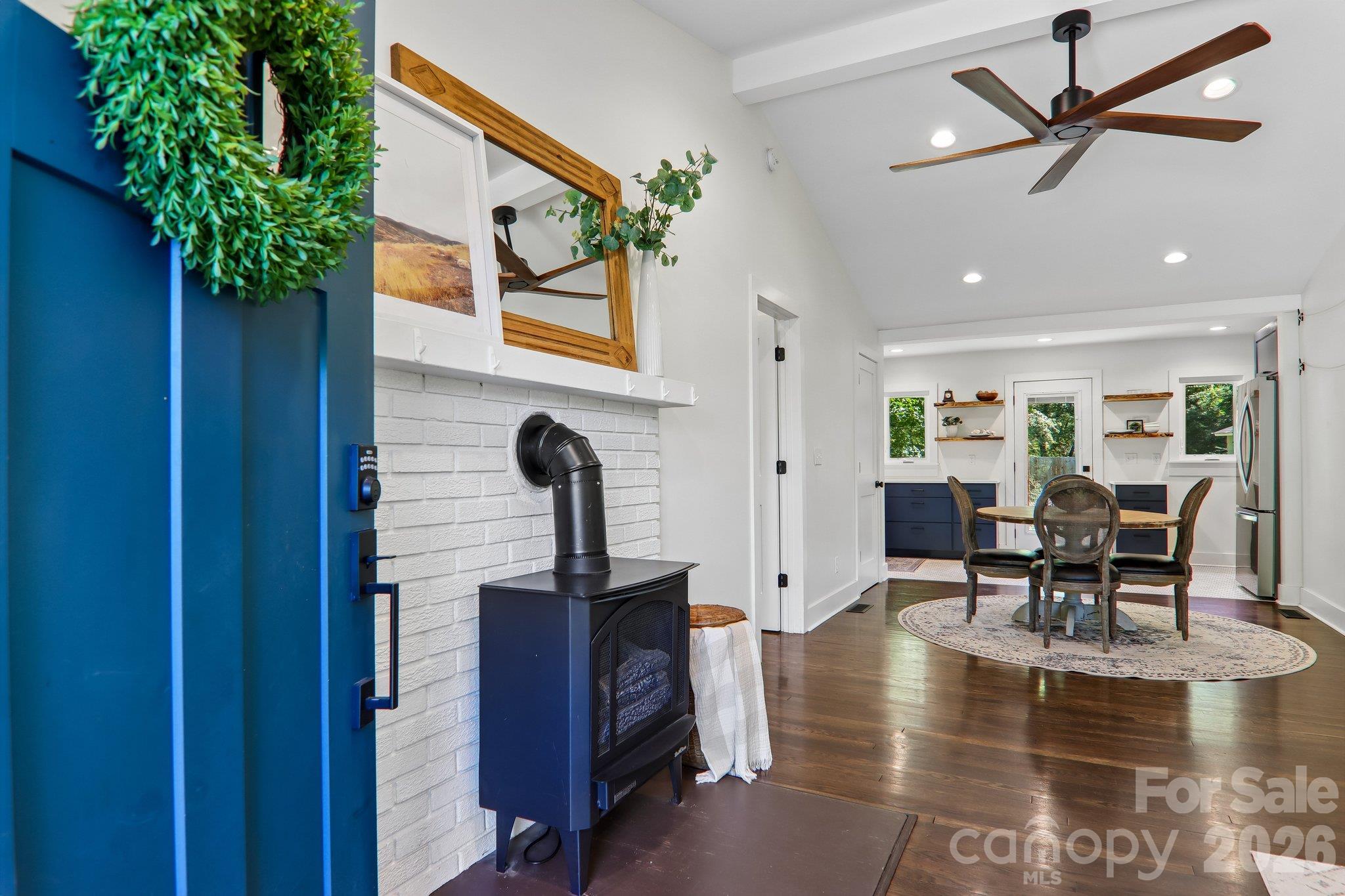 Open-plan living and dining area with a freestanding stove, round table, and navy kitchen cabinets.