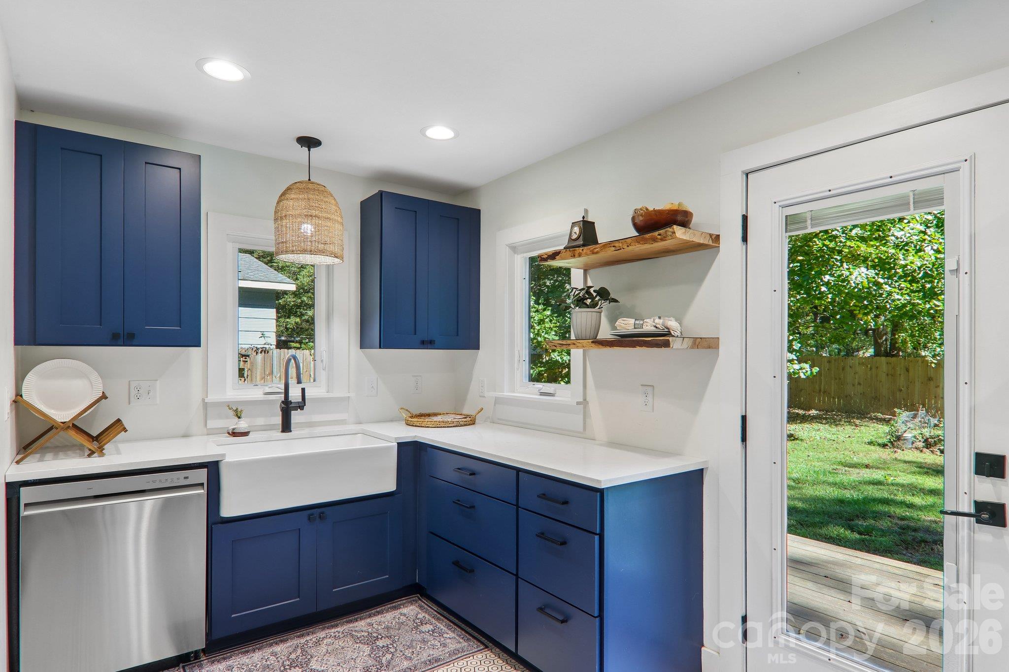 Kitchen with navy cabinets, a white farmhouse sink, and a glass door opening to the yard.