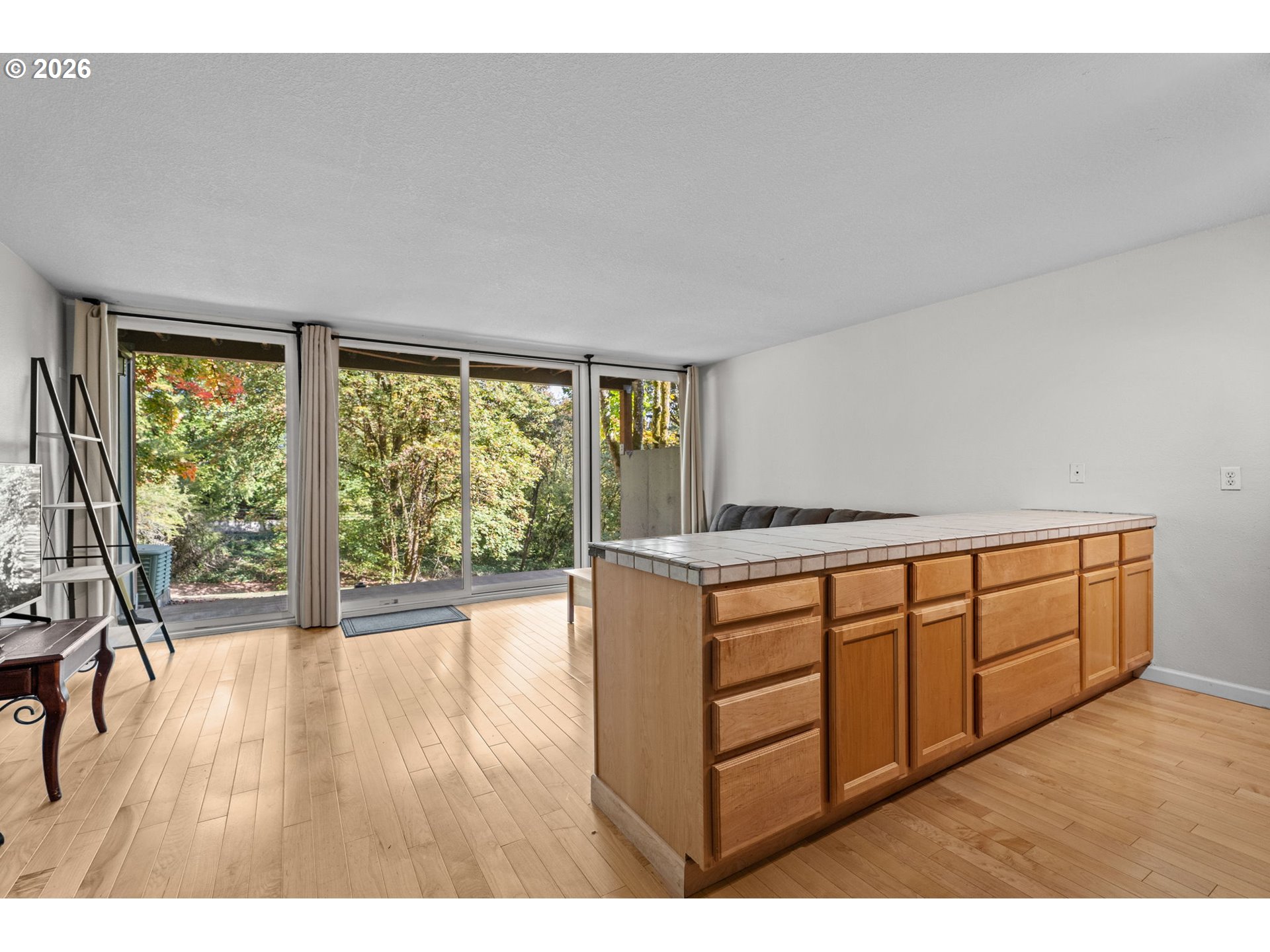 Kitchen with a tiled wood island and sliding glass doors overlooking trees.