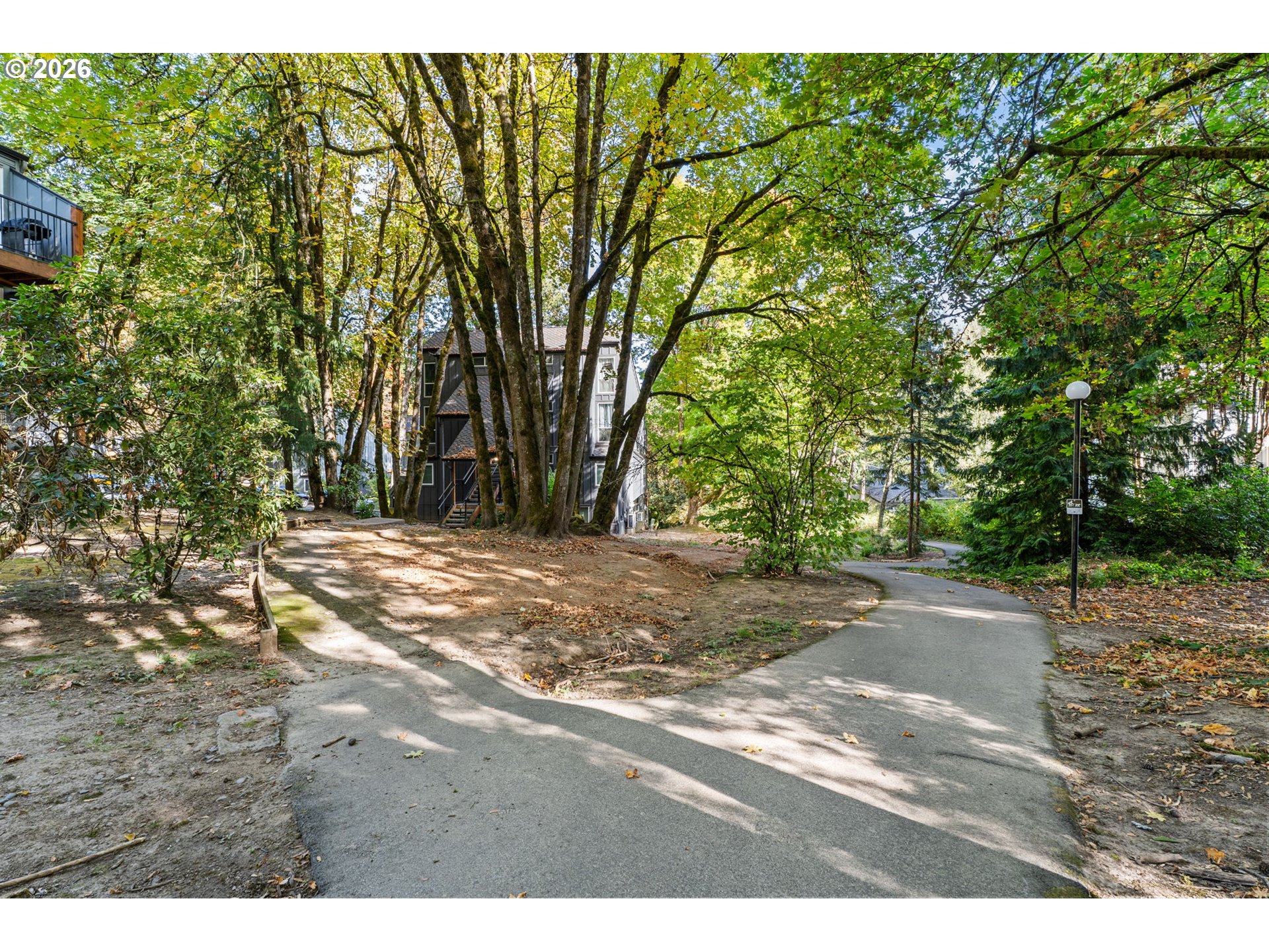 Residential building among mature trees beside a curving paved walkway.