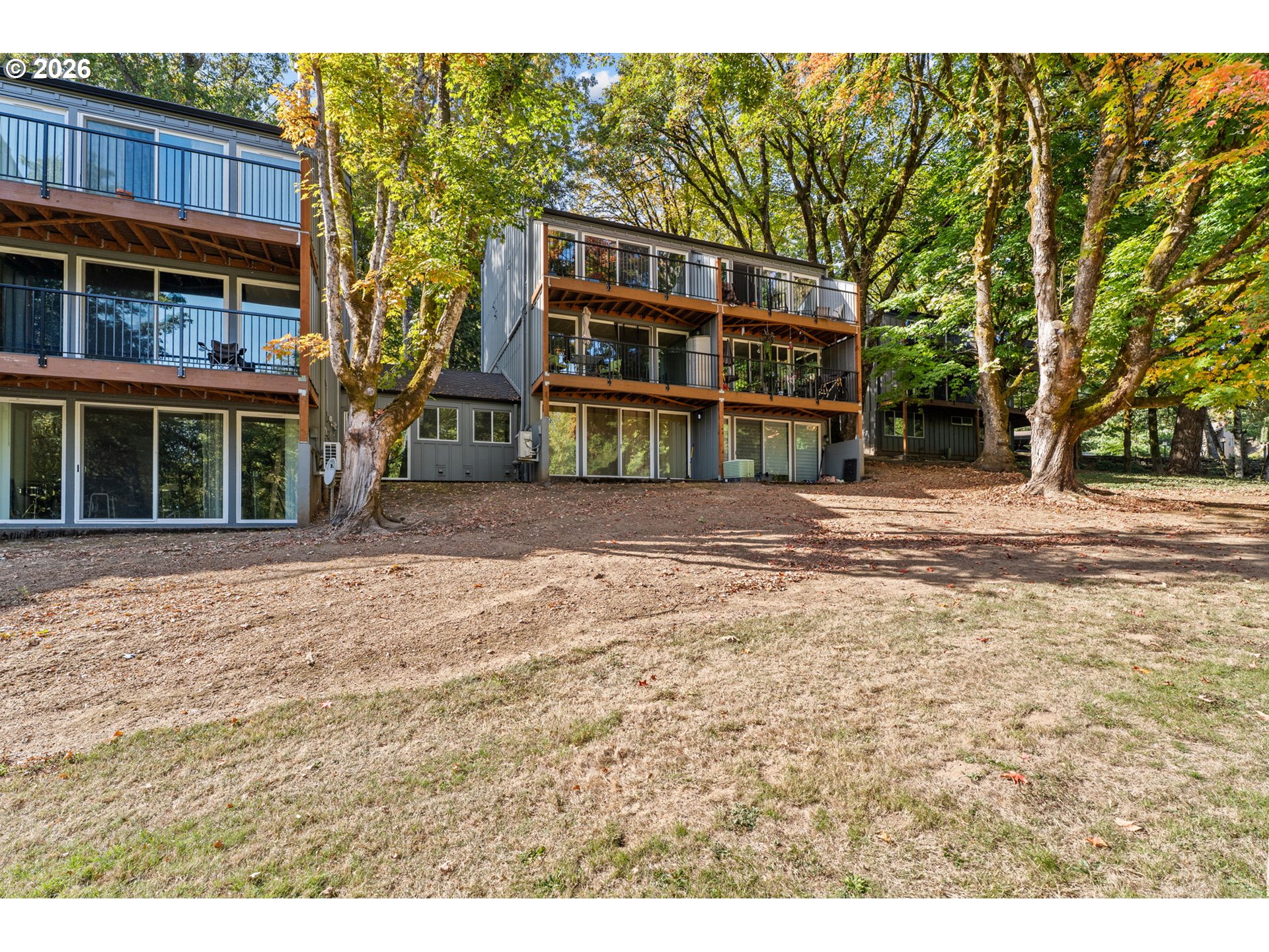 Multi-level residence with stacked balconies among mature autumn trees.