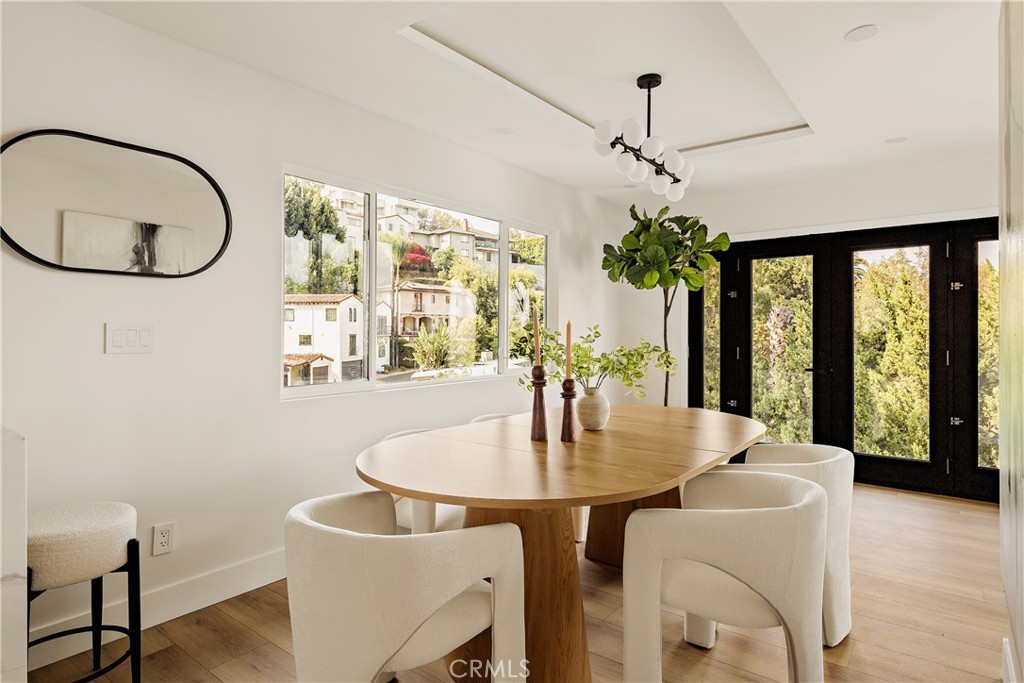 Dining room with a round wood table, upholstered chairs, and black-framed glass doors.