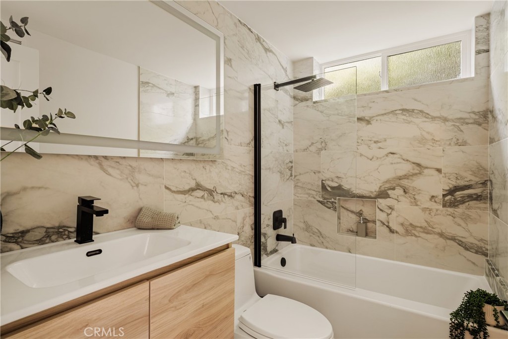 Bathroom with marble-patterned tile, a glass-screened tub and shower, and a light wood vanity.