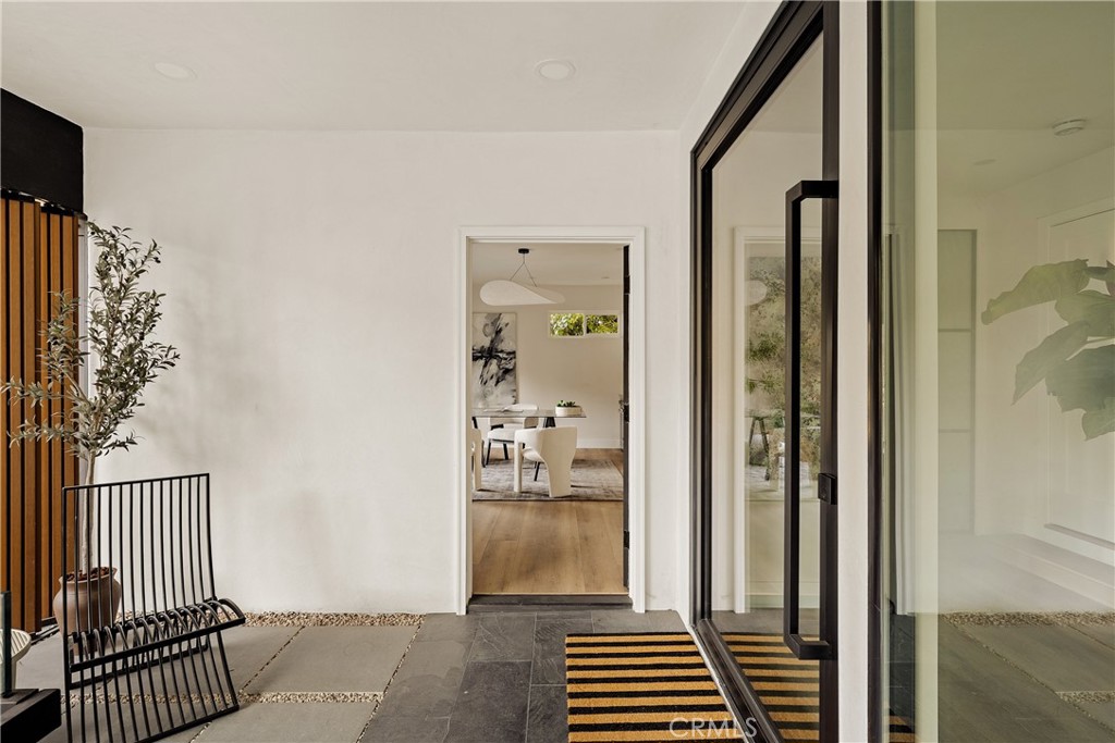 Home entry patio with black-framed glass doors, striped mat, and a view into the dining area.