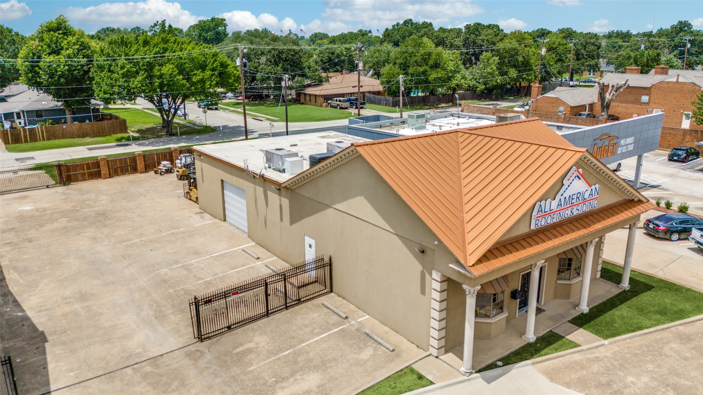 Commercial building with a copper-colored metal roof and an All American Roofing & Siding sign.