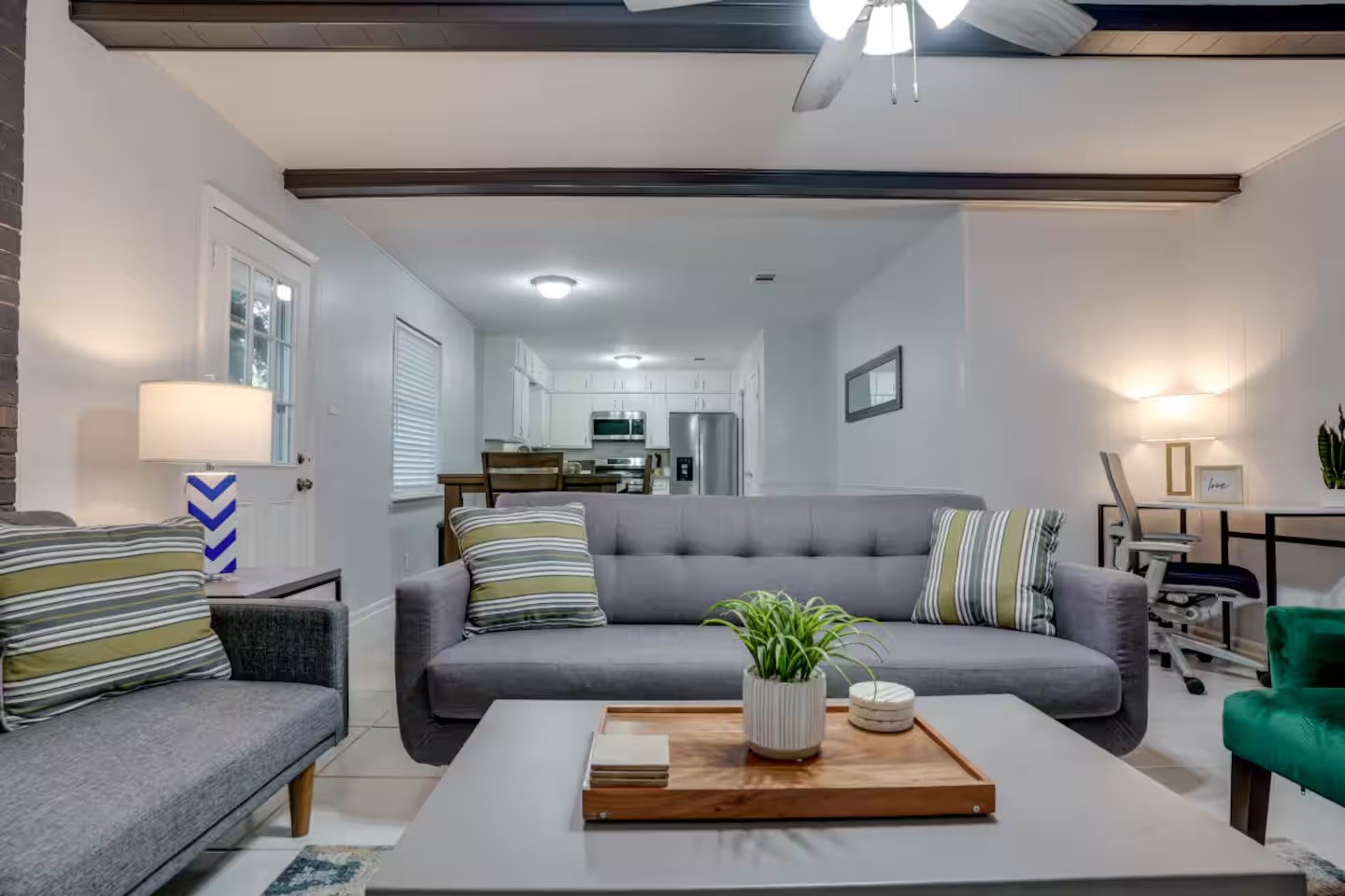 Staged living room with gray sofas and a view through to the white kitchen.